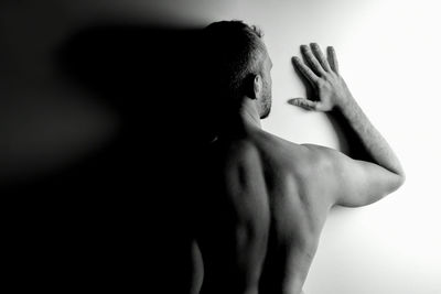 Rear view of shirtless man against wall