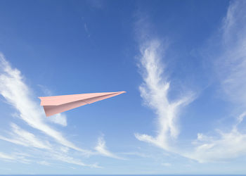 Low angle view of paper airplane flying against blue sky