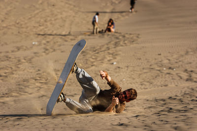 Happy man falling with sandboard at desert