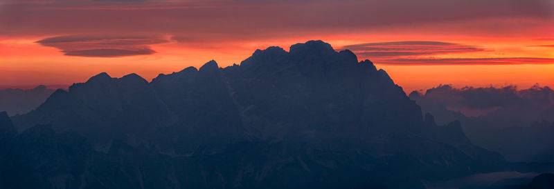 Scenic view of silhouette mountains against orange sky