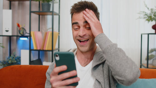 Surprise man using smart phone at home