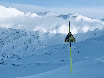 Scenic view of snow covered mountain against sky and warning sign