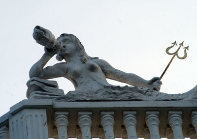 Low angle view of statue against building against sky