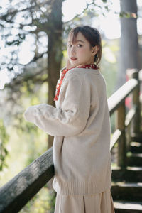 Young woman standing against trees