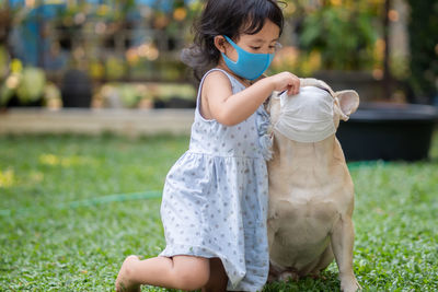 Little girl and her french bulldog wearing medical mask prevent pollution, flu and convid19 at park.