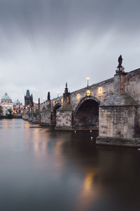 Arch bridge over river against sky in city