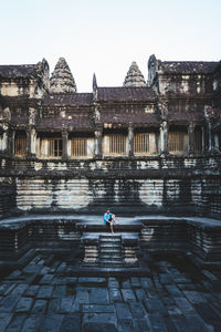 Full length of man sitting against historic building