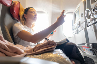 Woman holding camera while sitting at airplane