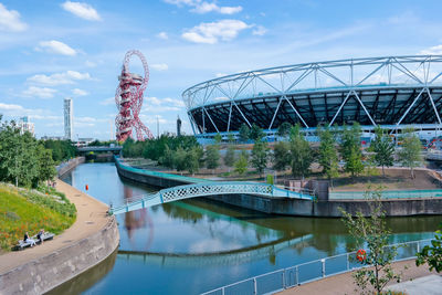 Bridge over river by ferris wheel against sky