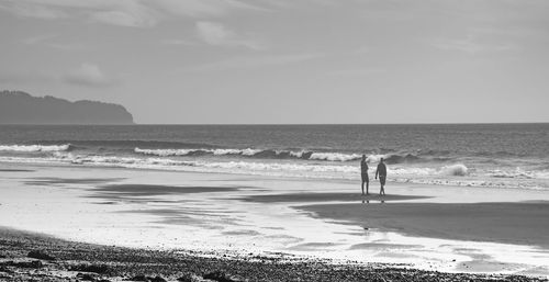 Woman standing on beach against sky