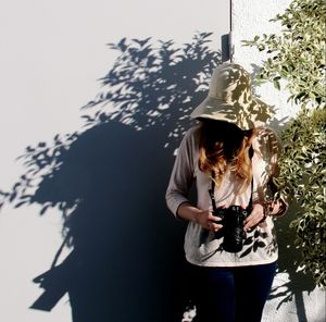 Female photographer standing with shadow against wall