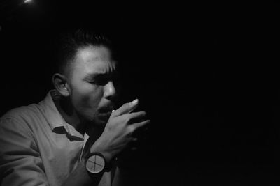 Portrait of young man against black background