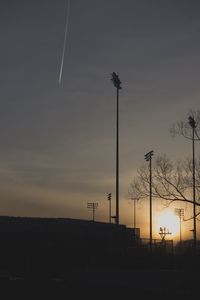 Low angle view of silhouette street lights against sky at sunset