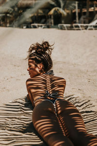 Portrait of happy woman relaxing on sand at beach