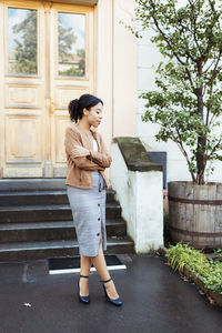 Portrait of young woman standing against window