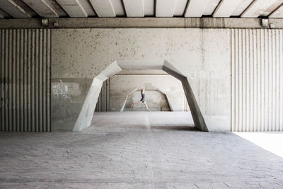 Side view of mid adult woman jumping under bridge