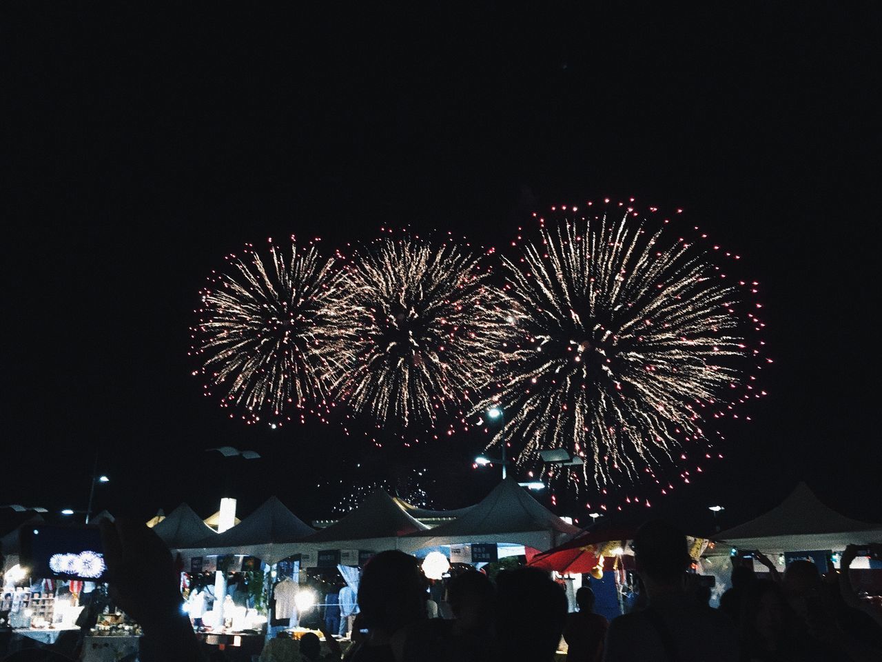 celebration, night, firework display, arts culture and entertainment, large group of people, event, firework - man made object, exploding, real people, illuminated, men, lifestyles, leisure activity, outdoors, crowd, long exposure, women, low angle view, built structure, sky, multi colored, group of people, city, clear sky, people