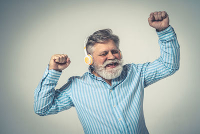 Man with arms raised standing against gray background