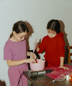 Two beautiful caucasian girls are baking cookies.