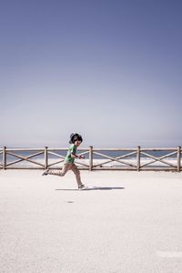 Full length of woman standing by sea against clear sky