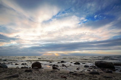 Rocks on beach against sky during sunset