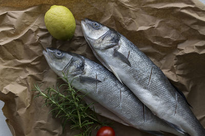 High angle view of fish with ingredients on brown paper