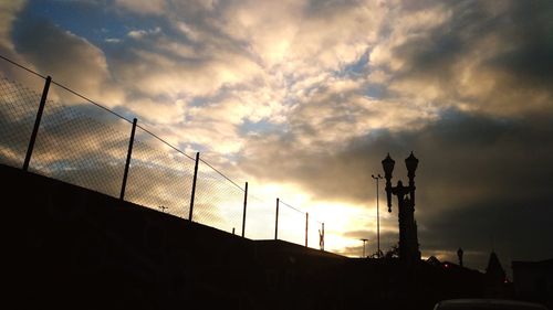 Low angle view of silhouette fence against sky during sunset