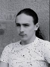 Close-up portrait of young man standing against wall