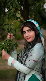 Portrait of beautiful woman standing against plants