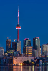 Communications tower in city against sky