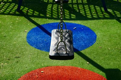 Close-up of swing hanging over grass in playground