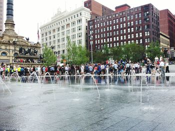 People at town square against sky in city