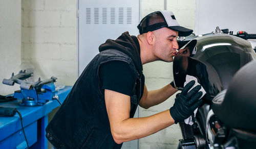 Mature mechanic kissing while cleaning motorcycle in garage