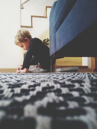 Cute boy playing while sitting on floor at home