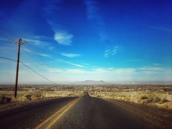 Road passing through landscape against blue sky