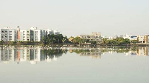 Reflection of buildings in city against clear sky