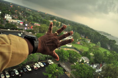 Close-up of hand against trees