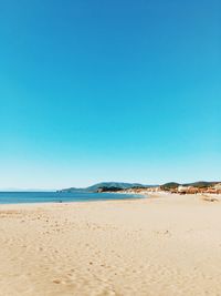 Scenic view of beach against clear blue sky