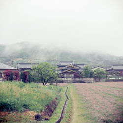 Built structure on field by buildings against sky