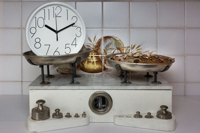 Close-up of clock and coins on weight scale