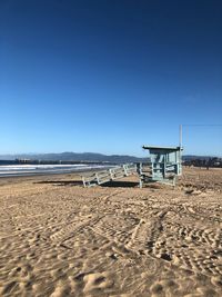 Lifeguard hut on beach against clear blue sky