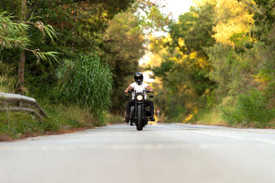 Young man on a vintage motorcycle on a mountain road at sunset