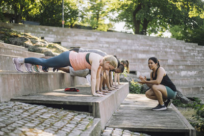 Female coach motivating team working out on steps