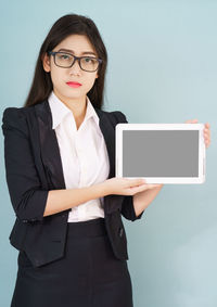 Portrait of a young woman using smart phone against white background