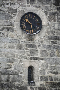 Low angle view of clock on stone wall