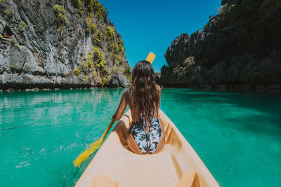 Rear view of woman on rock by sea