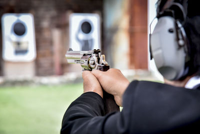 Midsection of man aiming gun during target shooting