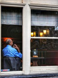 Rear view of man working at window