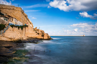 Rock formations by sea against sky