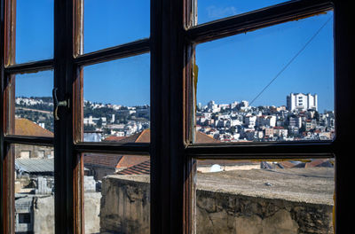 Cityscape against clear blue sky seen through window